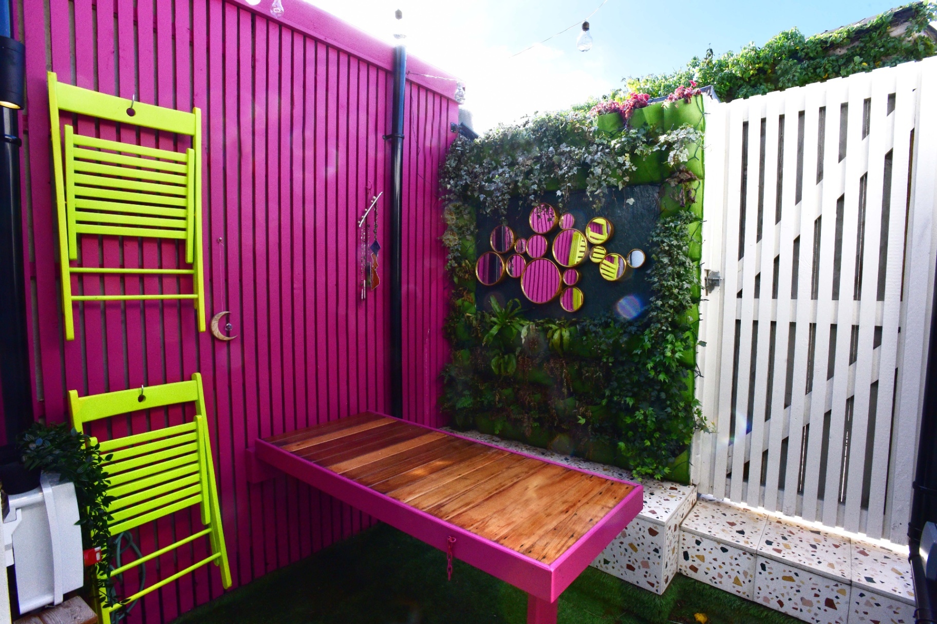 Vibrant pink garden fence with lime green folding chairs