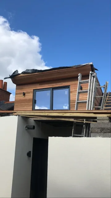 Cedar-clad extension mid-build with scaffolding